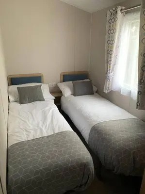 two beds in a small room with a window at Kellysholidayhomes NEW Malton 3 bedroom Caravan in Weeley