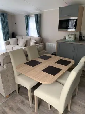 a dining table and chairs in a living room at Kellysholidayhomes NEW Malton 3 bedroom Caravan in Weeley