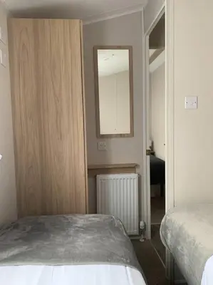 a bedroom with a bed and a mirror on the wall at Kellysholidayhomes NEW Malton 3 bedroom Caravan in Weeley