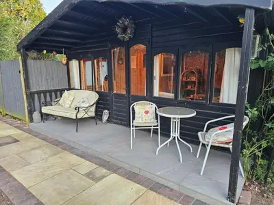 a black shed with two chairs and a table at Luxury Self-Catering and Sauna - Oaks Rest in Colchester