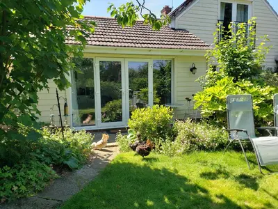a house with a conservatory with chickens in the yard at Luxury Self-Catering and Sauna - Oaks Rest in Colchester
