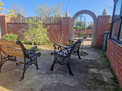 two park benches sitting next to a brick building at Primroses, Wood Farm in Shipdham
