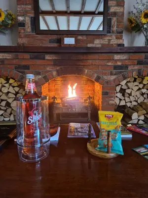a bottle of soda sitting on a table in front of a fireplace at Primroses, Wood Farm in Shipdham