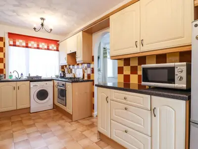 a kitchen with white cabinets and a microwave at 21 Crossways in Clacton-on-Sea