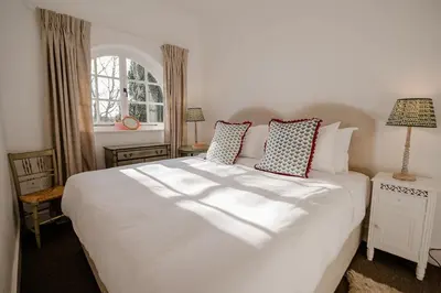 a bedroom with a large white bed and a window at Butley Priory Cottage in Woodbridge