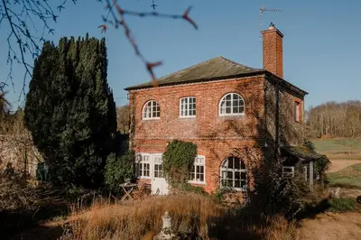 an old brick house with a chimney and a tree at Butley Priory Cottage in Woodbridge