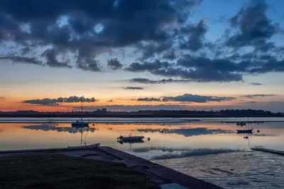 a sunset with boats in a body of water at Butley Priory Cottage in Woodbridge