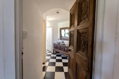 a hallway with a wooden door and a checkered floor at Butley Priory in Woodbridge