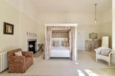 a bedroom with a canopy bed and a chair at Butley Priory in Woodbridge