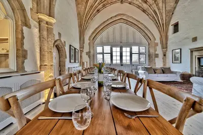 a dining room with a long table with plates and glasses at Butley Priory in Woodbridge