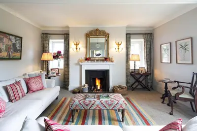 a living room with a white couch and a fireplace at Butley Priory Farmhouse in Woodbridge