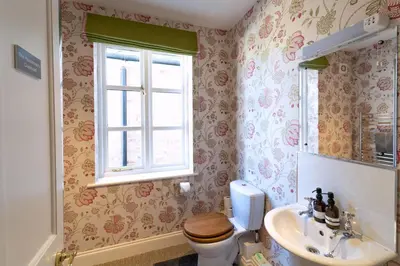 a bathroom with a toilet and a sink and a window at Butley Priory Farmhouse in Woodbridge