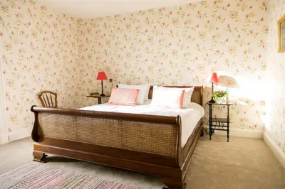 a bedroom with a bed with pink floral wallpaper at Butley Priory Farmhouse in Woodbridge