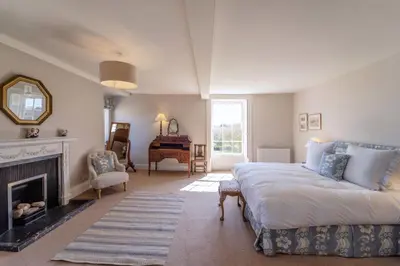 a living room with a bed and a fireplace at Butley Priory Farmhouse in Woodbridge