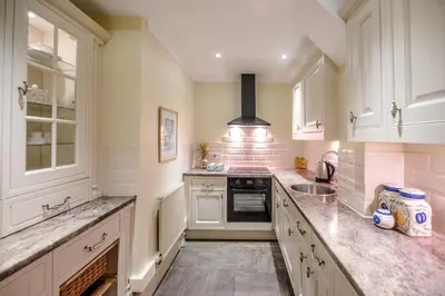 a kitchen with white cabinets and granite counter tops at Villa Verde in Aldeburgh