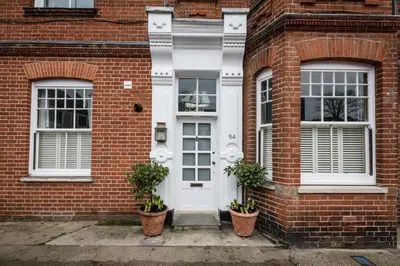 a brick house with two windows and two potted plants at Villa Verde in Aldeburgh