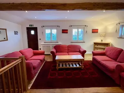 a living room with red couches and a table at The Cart Lodge at Lee Wick Farm Cottages & Glamping in Saint Osyth