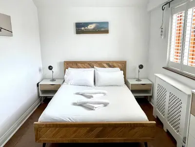 a bedroom with a bed with white sheets and two windows at The Cart Lodge at Lee Wick Farm Cottages & Glamping in Saint Osyth