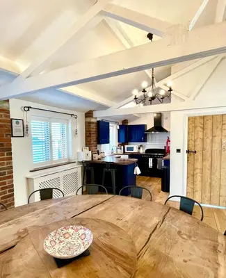 a dining room and kitchen with a wooden table at The Cart Lodge at Lee Wick Farm Cottages & Glamping in Saint Osyth