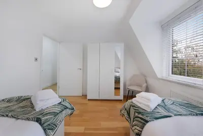a white room with two beds and a window at Roomy One bed loft apartment in Bishops Stortford