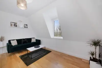 a living room with a green couch and a table at Roomy One bed loft apartment in Bishops Stortford