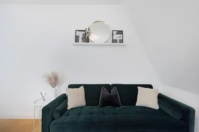 a green couch in a living room with a mirror at Roomy One bed loft apartment in Bishops Stortford
