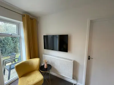 a living room with a chair and a tv on a wall at One Bed Apartment Stevenage in Stevenage