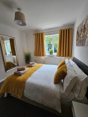 a bedroom with a large bed and a mirror at One Bed Apartment Stevenage in Stevenage
