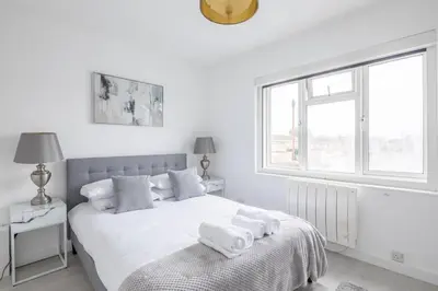 a white bedroom with a bed with towels on it at Lovely 2 bedroom apartment - ideal location in Cambridge