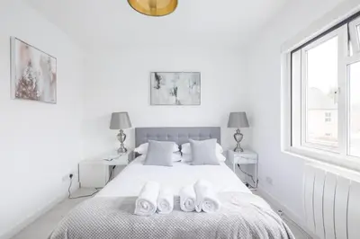 a white bedroom with a bed with white towels on it at Lovely 2 bedroom apartment - ideal location in Cambridge