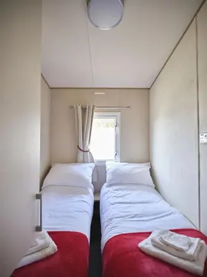 two beds in a small room with a window at Lighthouse Holiday Retreat in West Mersea