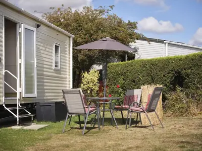three chairs and a table with an umbrella in a yard at Lighthouse Holiday Retreat in West Mersea