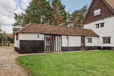 a large white house with a grass yard at The Retreat in Tibenham