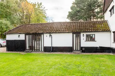 a white and black house with a green yard at The Retreat in Tibenham