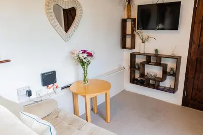 a living room with a vase of flowers on a table at The Retreat in Tibenham