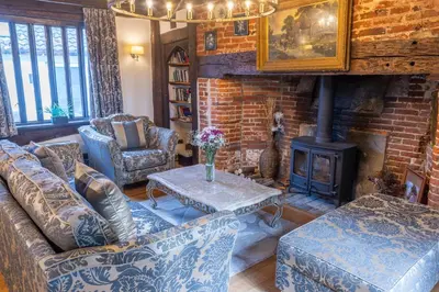 a living room with couches and a wood stove at Amazing Spa Country House with Indoor Pool, Sauna and Steam Room in Tibenham