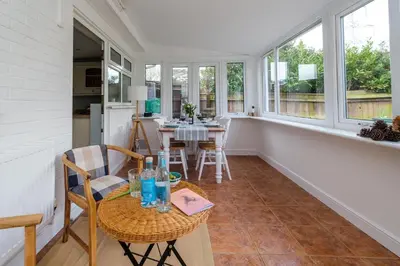 a dining room with a table and chairs and windows at The Lodge, Aldringham in Aldringham