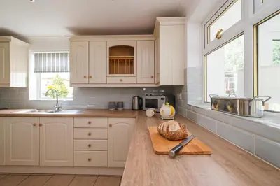 a kitchen with white cabinets and a cutting board at The Lodge, Aldringham in Aldringham