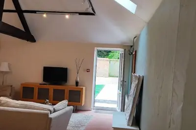 a living room with a couch and a tv at 2 Bed Barn conversion in Tibenham