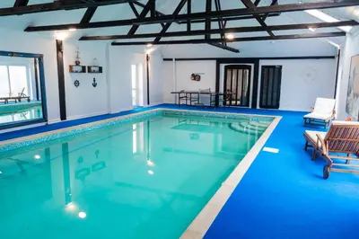 a large swimming pool with blue water at 2 Bed Barn conversion in Tibenham