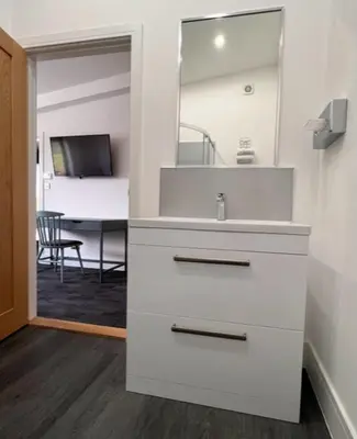 a white bathroom with a sink and a mirror at Withers Farm Apartments in Mount Bures