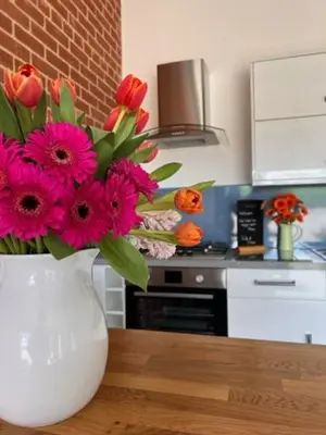 a white vase with pink flowers on a table in a kitchen at Withers Farm Apartments in Mount Bures