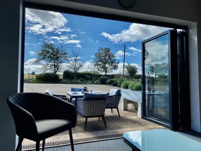 a patio with a table and chairs and a large window at Withers Farm Apartments in Mount Bures