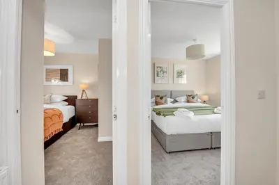 a white bedroom with two beds and a mirror at The Grange Luxe2, 5 Bedroom House,Spacious,contractor,family,Internet,free parking,group,study,relocation,easily accessible in Ipswich,Kesgrave in Ipswich