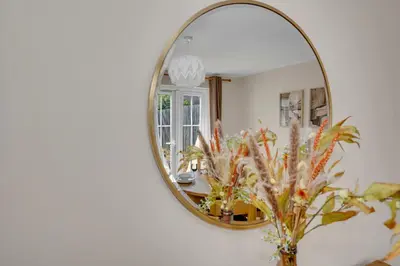 a mirror on a wall with a vase with flowers at The Grange Luxe3, 4 Bedroom House,5-beds,Spacious,contractor,family,Internet,free parking,group,study,relocation,easily accessible in Ipswich,Kesgrave in Ipswich