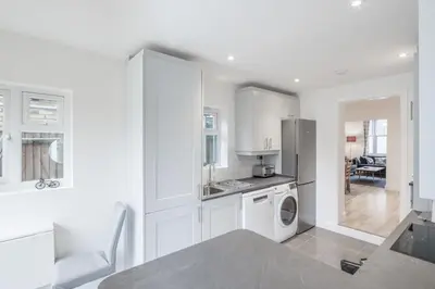 a kitchen with white cabinets and a washer and dryer at Refurbished High Spec CENTRAL Family Home in Cambridge