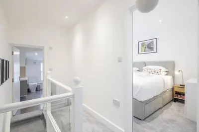 a white bedroom with a bed and a staircase at Refurbished High Spec CENTRAL Family Home in Cambridge