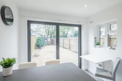 a white dining room with a table and a window at Refurbished High Spec CENTRAL Family Home in Cambridge