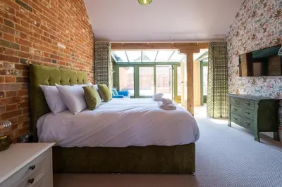 a bedroom with a large bed and a brick wall at Alde Bay Farm - Barn Owl Sanctuary in Aldeburgh