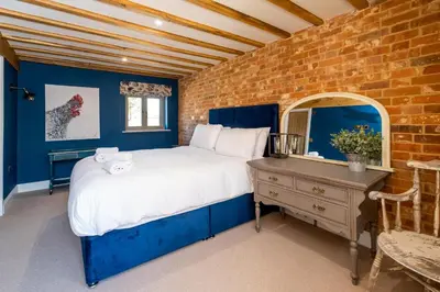 a bedroom with a large bed and a brick wall at Alde Bay Farm - Barn Owl Sanctuary in Aldeburgh